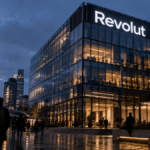 Sede di Revolut al crepuscolo con logo aziendale illuminato sulla facciata nel quartiere finanziario, simbolo del cyberattacco con furto dati e uso dell'infrastruttura delle forze di polizia italiane.